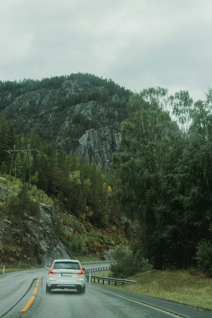 Witte auto op een natte bergweg door een bos